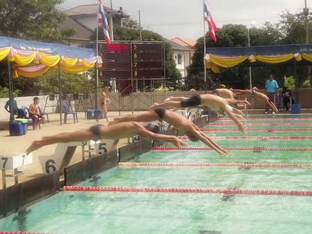 Young swimmers leap off the blocks at the start of a race. 