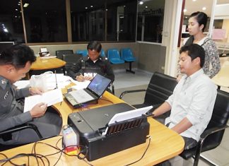 Amornthep Yomchaiyapum (seated right) is booked for possession of a loaded weapon.