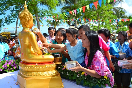 Young and old gather to pour lustral water on the Buddha.