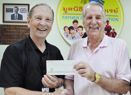 Brother Denis Gervais, vice president of the Father Ray Foundation, receives the donation from William Macey, charity chairman at the Pattaya Sports Club.