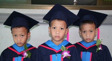Three brothers, identical triplets, don’t look too happy in their graduating gowns.