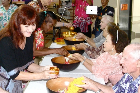 Guest of Honor Madame Satil Kunplome receives the traditional Songkran blessing from PCEC member Janet Smith, while her husband Richard Smith receives the same from Pattaya Blatt’s editor, Elfi Seitz.