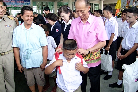 Gov. Khomsan Ekachai helps a youngster with his school backpack during the launch of Chonburi’s mobile-services program. 