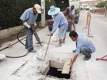 Sanitation workers clear drains and replace iron grates on Second Road in preparation of the coming rainy season. 