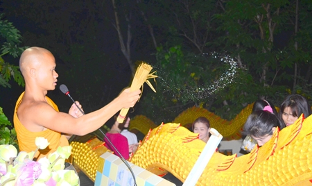 A Buddhist monk sprinkles holy water on the faithful at Wat Khao Phra Yai.