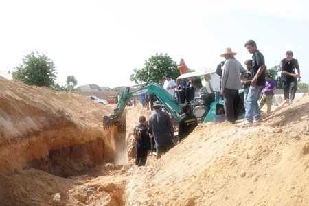 Rescue workers and police use a backhoe to search for buried construction worker Rattana Sujritphakdee.