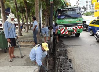 Sanitation Engineers clean dirt, garbage and sand out of the drainage pipes on Beach Road in Central Pattaya.