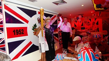 The “British queen from Pattaya,” John, alias Dolly Sister, together with the relay runner is welcomed by manager David Kerridge. 