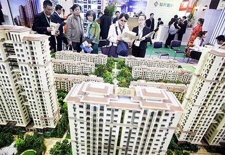 People look at models of new residential developments for sale at a real estate fair in Beijing, China. (EPA/Diego Azubel) 