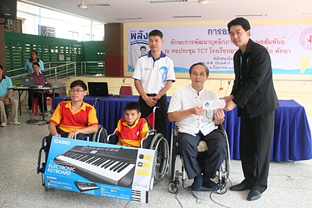 Porames Ngampiches, MP of Chonburi region 7, presents a cash donation and two electronic keyboards to Professor Udomchok Churat, director of Pattaya Redemptorist Vocational School for the Handicapped for use by the students in their studies and during recreation hours.