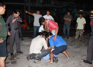 Police, unable to subdue the rock thrower, look on whilst civilians provide their own justice.