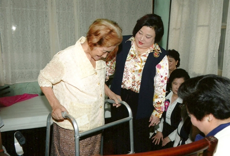 HRH Princess Soamsawalee graciously helps an elderly patient.