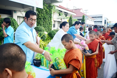 Sonthaya Kunplome (left), former minister of tourism and sports, along with his wife, Cultural Minister Sukumol Kunplome (2nd left), offer alms to young monks in front of Banglamung City Hall.