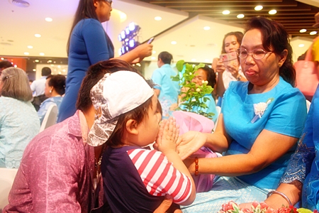 A young boy ‘wais’ his grandmother after his parents had already presented jasmine flowers, one of the activities in the Love to 80 Outstanding Mothers in Pattaya celebration at Central Festival Pattaya Beach.