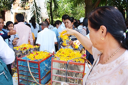 People earn merit by showering flowers over bird cages to spare their lives.