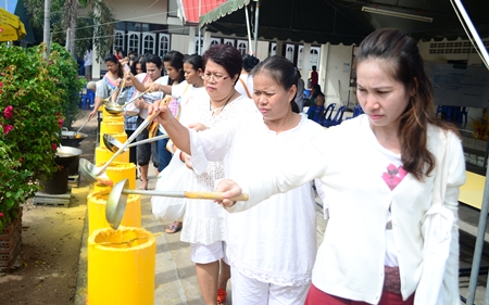 Faithful Buddhists make merit by pouring candle wax into molds to make Lent candles on Asalaha Bucha day at Wat Nong Or.
