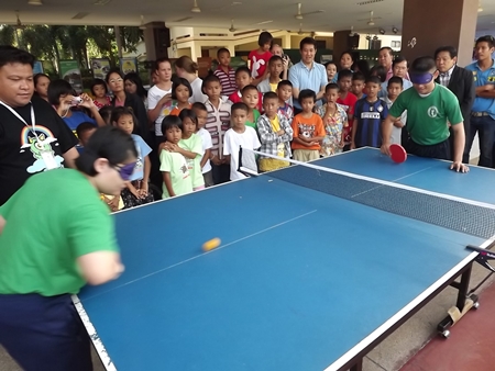 The crowd watches in awe as two students play a game of blindfolded table tennis. 