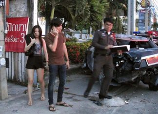 Alleged drunk driver Thanitpong Theppawat (on phone) and his allegedly equally drunk university student girlfriend stand by as police check the wrecked vehicle.