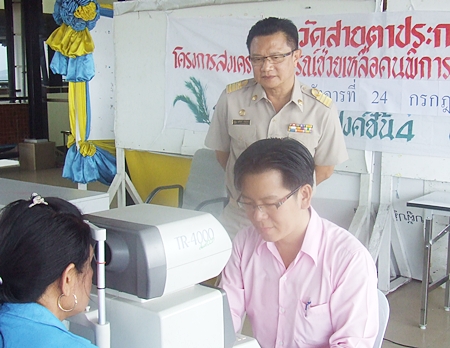 Deputy Mayor Verawat Khakhay looks on as Pawit Chotthonawuth, owner of Mahanakhorn spectacle shop, performs a free eye exam.
