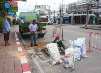 Workers in Soi Naklua 16/1 fix the collapsed drainage lids.