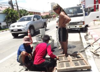 City workers take turns descending into the drains to do the dirty work, passing up sand to be hauled away.