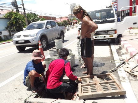 City workers take turns descending into the drains to do the dirty work, passing up sand to be hauled away. 
