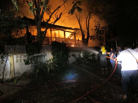 Firefighters use four fire engines to fight the blaze to prevent the wooden-house fire from spreading to neighboring homes. 