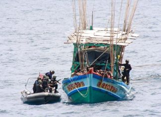 Enforcement officers from Royal Thai Navy patrol ships move in and secure a Vietnamese fishing boat caught illegally fishing in Thai waters.