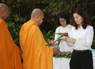Sudachan Aprirattanapimonchai, Director of Finance & Business Support, leads employees to offer alms to monks at the Havana Bar & Restaurant.