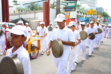 White clad marchers sound the gong to alert people in the area that the parade is marching through.