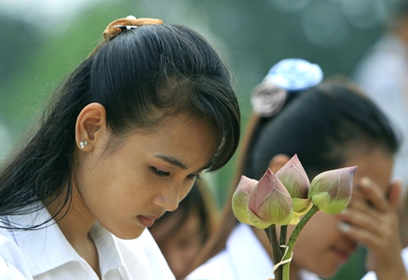 Cambodian students hold lotus flowers while praying in front of the main gate of the Royal Palace in Phnom Penh, Cambodia, to mourn the death of former King Norodom Sihanouk Tuesday, Oct. 16, 2012. (AP Photo/Heng Sinith)