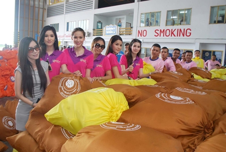 Miss Tiffany Universe pageant winners help Royal Thai Navy personnel pack bags of emergency rations. 