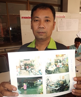 Flood victim Prasert Sornkhum, 43, shows photos of the flood damage at his home, evidence to support receiving relief from City Hall. 