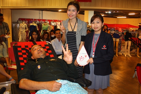 Pol. Lt. Gen. Passorn Ingsrangkul Na Ayuthaya (seated), special advisor to the Royal Thai Armed Forces, is cheered on by Phanisra Sukhjinda (right), acting chief of National Blood Center 3, and Kusuma Aebata (center), promotion officer of Central Festival Pattaya Beach as he gives blood. 