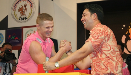 Pattaya mayor Ittipol Kunplome, right, tests his arm-wrestling prowess against one of the match referees.
