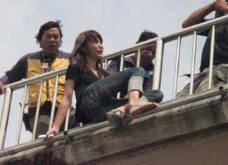 A rescue worker sneaks in behind the grieving woman and grabs her while others move in to help.