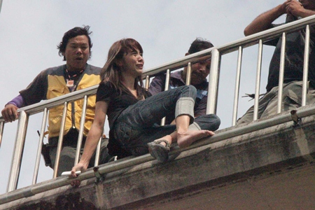 A rescue worker sneaks in behind the grieving woman and grabs her while others move in to help. 