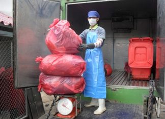 Nattapol Theerawuthiworawet carefully weighs medical waste in preparation to properly dispose of it.