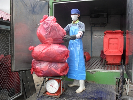 Nattapol Theerawuthiworawet carefully weighs medical waste in preparation to properly dispose of it. 