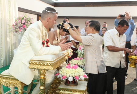 Dr. Vongbhum Vanasin performs the sacred ritual of bonding the bride and groom with blessings for a happy life together.
