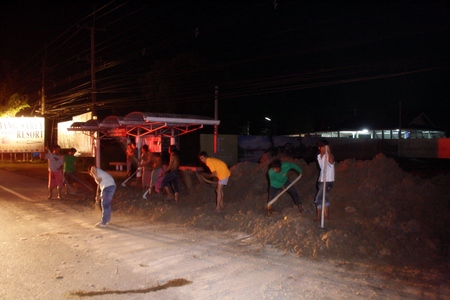 Workers hurriedly remove the dangerous pile of dirt before anyone else is injured. 