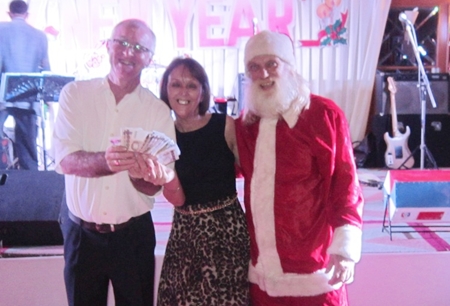 A happy 50/50 winner gets an early Christmas gift from Santa and Tony Oakes.