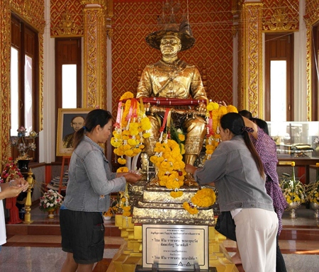 At the King Taksin statue, people present fruit, pig heads, ducks and chicken, while others gild the statue with gold leaf. 