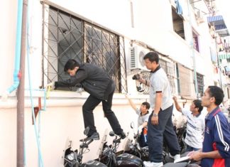 Investigators inspect the scene of a shotgun blast into Pattaya’s new police chief’s residence.