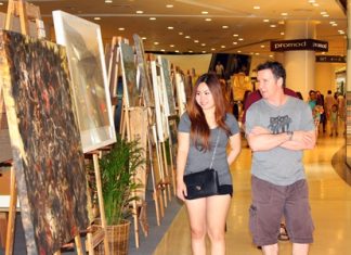 Tourists admire paintings at the 3rd art exhibition in honor of HM the King in Central Festival Pattaya Beach.