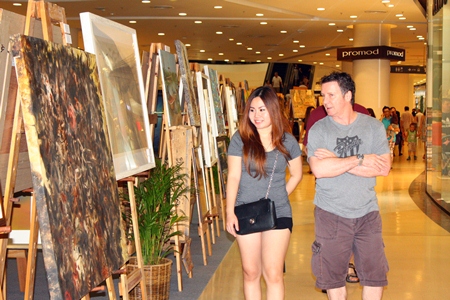 Tourists admire paintings at the 3rd art exhibition in honor of HM the King in Central Festival Pattaya Beach.