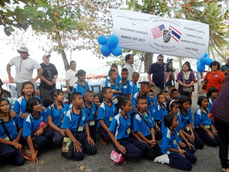 Kids wearing blue shirts from Nonsomboon School arrive at Jomtien Beach. Local volunteers can be seen in the background.