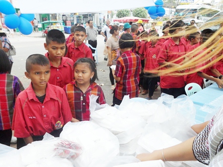 Kids from Thamang School, in red shirts, and kids from Sakae School, in plaid shirts, picking up their lunches.