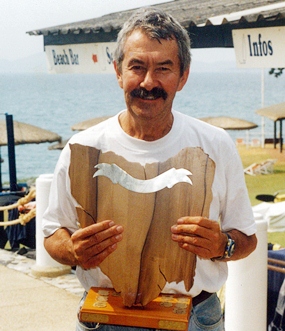 Peter Cummins displays the coveted Pattaya Mail PC Classic trophy.  Made of a rare timber sourced in Tasmania and carved by a craftsman there, it is in the shape of the small island itself.