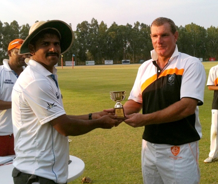 Simon Phillbrook (right) presents a trophy to the captain of the RAW Cricket Club following their match at Thai Polo Club, Saturday, March 2.